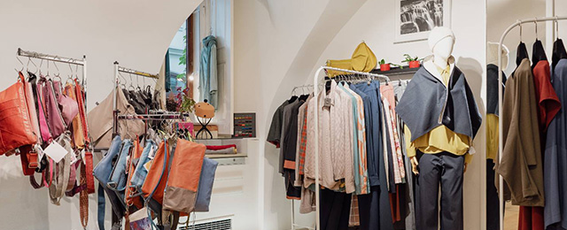Innenansicht Boutique in hellen offenen Stil mit Kleiderstangen und Handtaschen.
